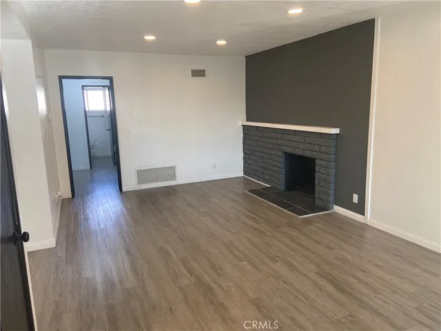 an empty room with wooden floor and fireplace