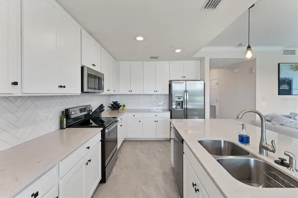 a kitchen that has a sink cabinets counter space and appliances