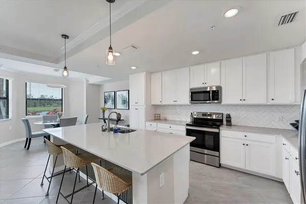 a kitchen with stainless steel appliances kitchen island granite countertop a stove a sink a dining table and chairs with wooden floor