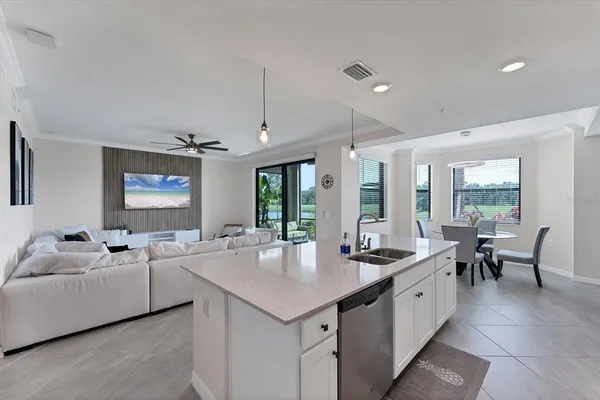 a large dining hall with stainless steel appliances kitchen island granite countertop a sink and chairs