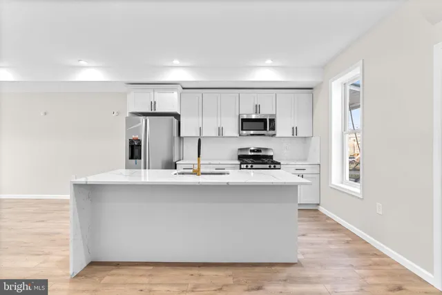 a kitchen with stainless steel appliances a sink a stove a refrigerator cabinets and a window