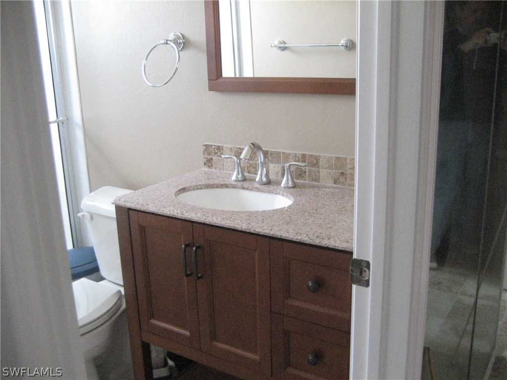 18461 Geranium Road Fort Myers, FL 33967 - Photo 15 of 17 a bathroom with a granite countertop sink a toilet and a mirror
