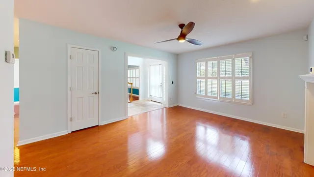 a view of an empty room with wooden floor and a window