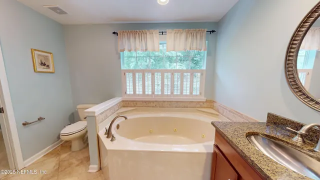 a bathroom with a granite countertop sink and a toilet