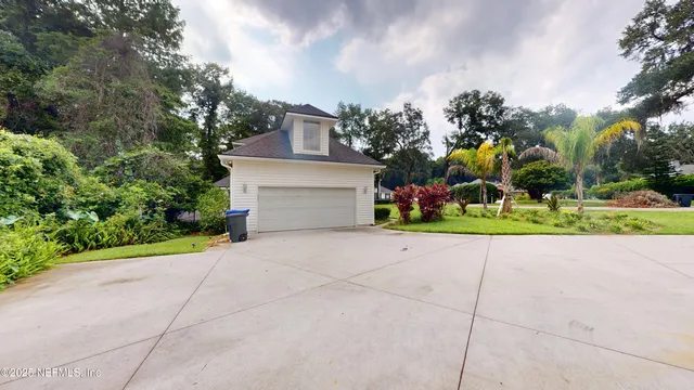 a view of yellow house with a yard and potted plants