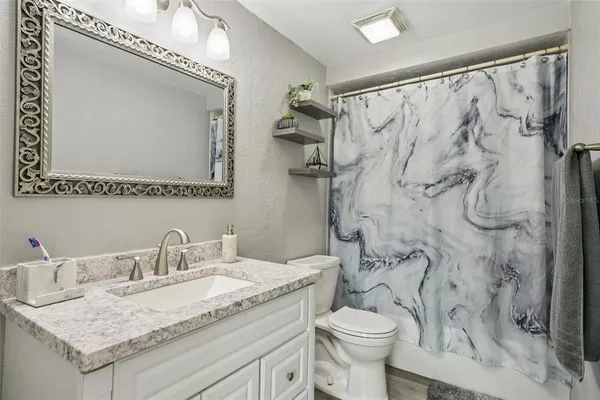 a bathroom with a granite countertop sink a toilet and a mirror