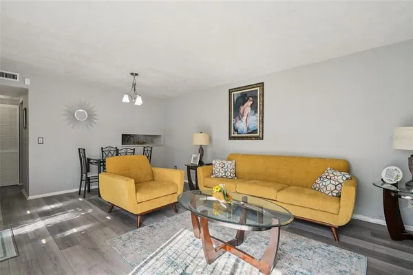 a living room with furniture and a dining table with wooden floor
