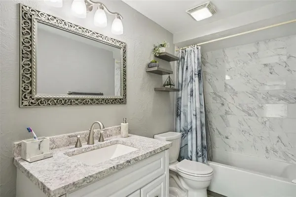 a bathroom with a granite countertop sink a toilet and a mirror