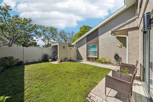 a backyard of a house with table and chairs and potted plants