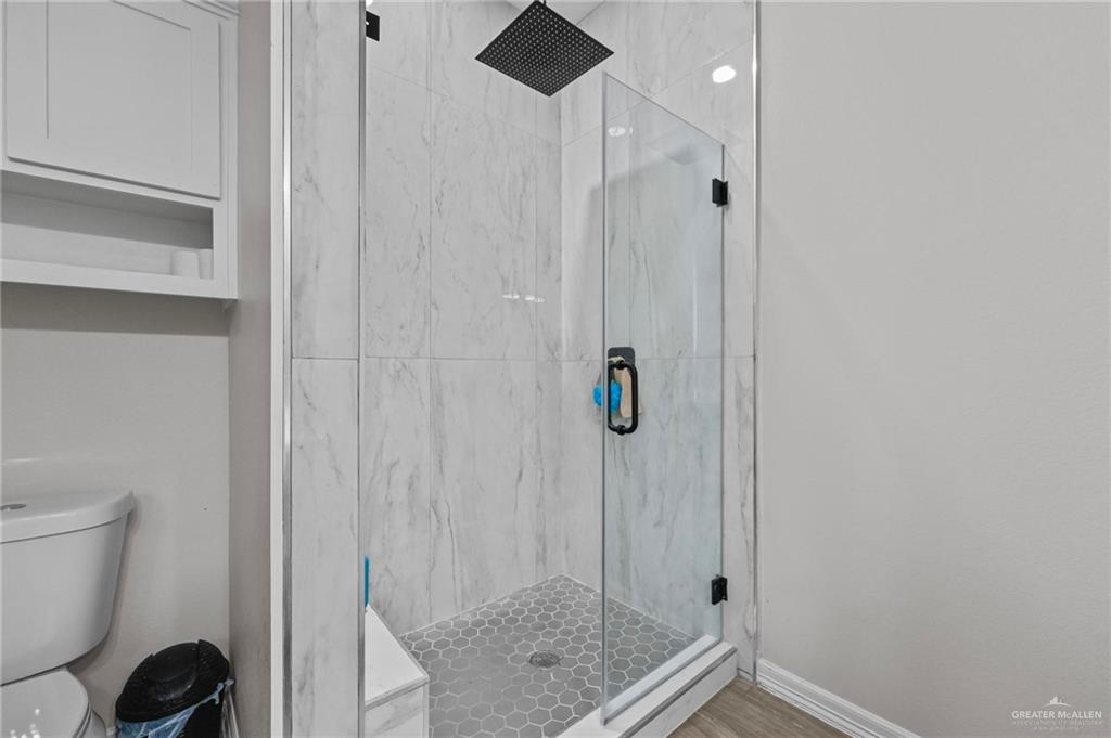 23247 Uresti Road Edinburg, TX 78542 - Photo 10 of 18 Glass-enclosed shower with a rainfall showerhead, large format tile surround, and hexagonal floor tiles
