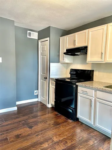 a kitchen with granite countertop a stove a sink and a microwave