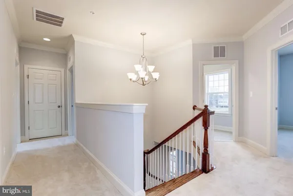 a view of a hallway to a window and chandelier