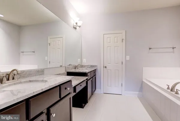 a bathroom with a granite countertop sink a large mirror and a bathtub