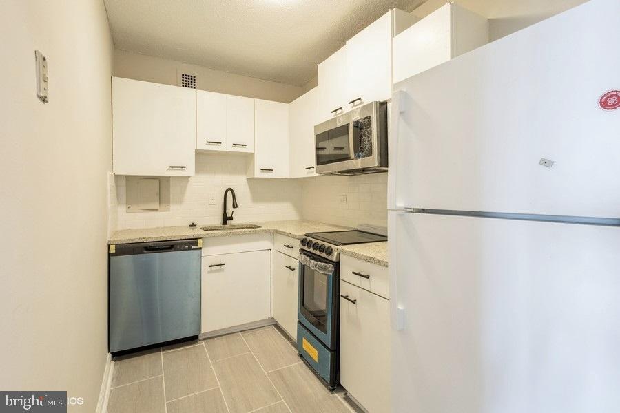 1301 Delaware Avenue Southwest, Unit N720 Washington, DC 20024 - Photo 10 of 20 a kitchen with stainless steel appliances granite countertop white cabinets a microwave a sink and a refrigerator