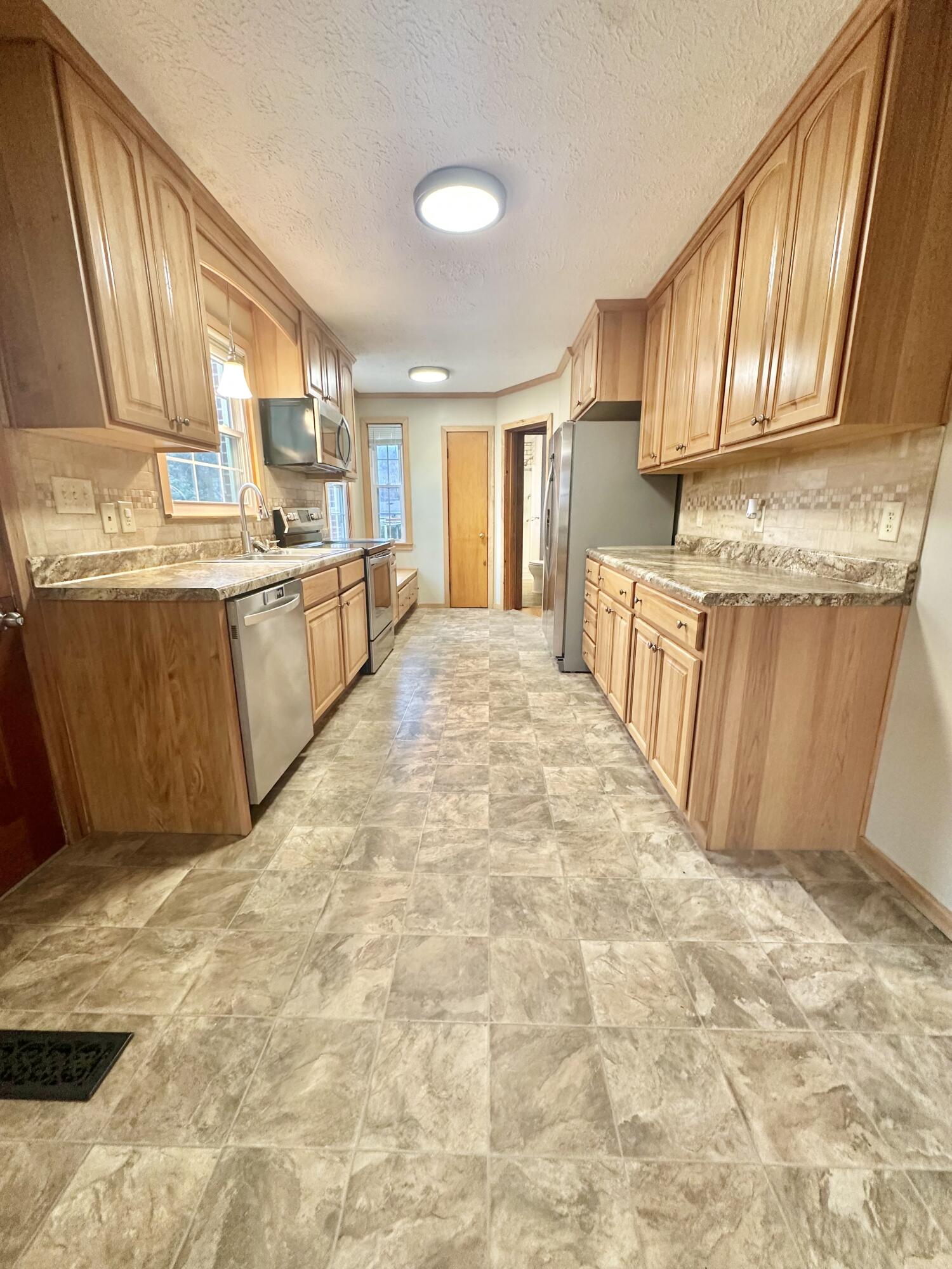2714 Jackson River Road Covington, VA 24426 - Photo 25 of 54 a large white kitchen with granite countertop a sink a stove a refrigerator with grey cabinets and wooden floor