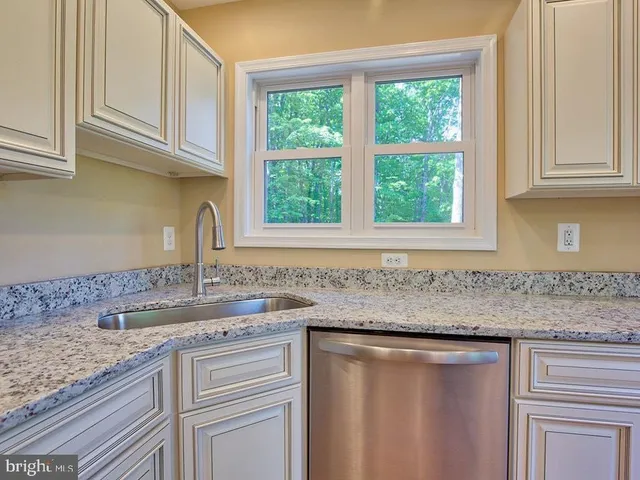 a kitchen with granite countertop a sink window and cabinets