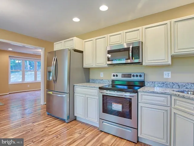 a kitchen with stainless steel appliances granite countertop a stove a refrigerator and a microwave