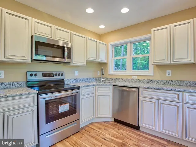 a kitchen with stainless steel appliances granite countertop a stove microwave and sink
