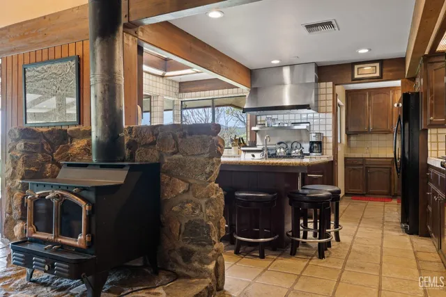 a large kitchen with granite countertop a dining table chairs wooden cabinets and stainless steel appliances