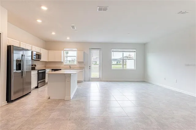 a view of kitchen with granite countertop refrigerator and window