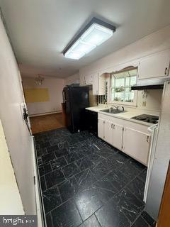 7717 Pearsons Corner Road Dover, DE 19904 - Photo 10 of 17 a kitchen with a sink a stove a refrigerator and black cabinets