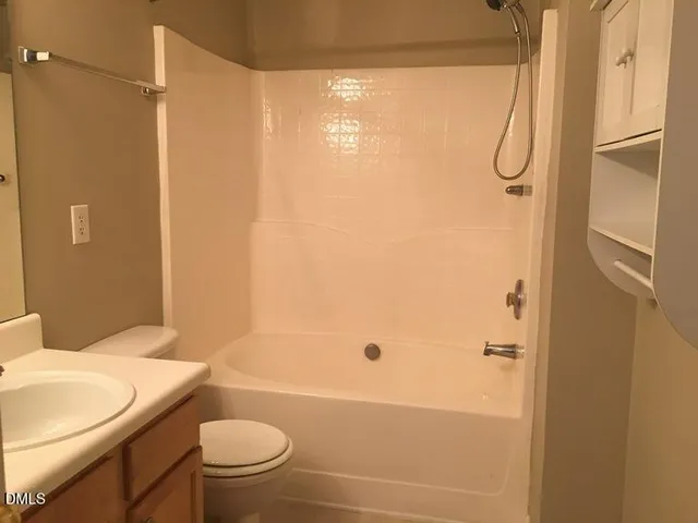 a bathroom with a granite countertop bathtub shower sink vanity and a toilet
