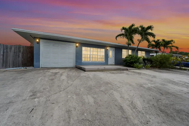 a view of a house with a yard and palm trees