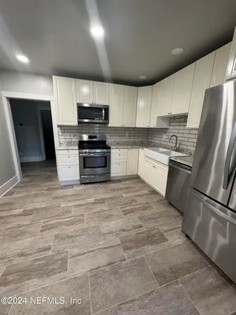 a kitchen with stainless steel appliances granite countertop a refrigerator a stove a sink and a microwave