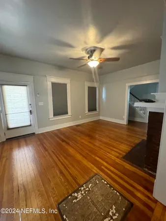 a view of an empty room with window and wooden floor