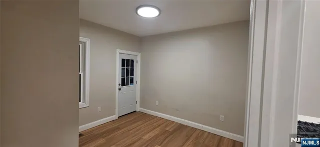 a view of an empty room with wooden floor and closet