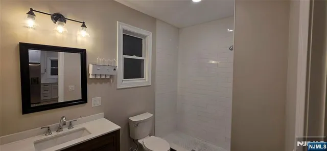 a bathroom with a toilet sink vanity and mirror