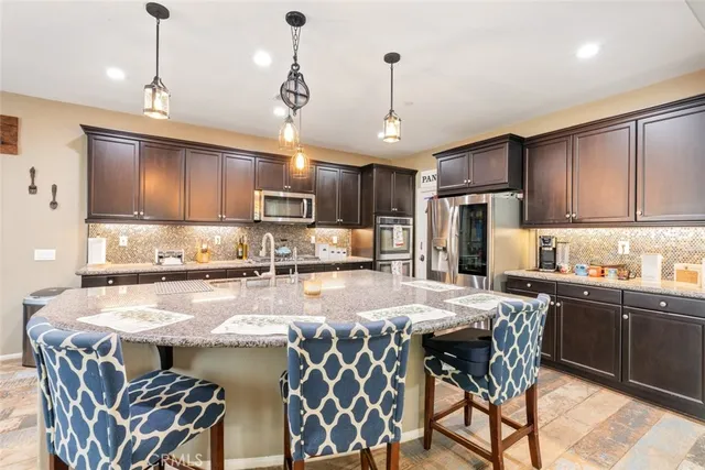 a kitchen with stainless steel appliances granite countertop a sink a stove a table and chairs