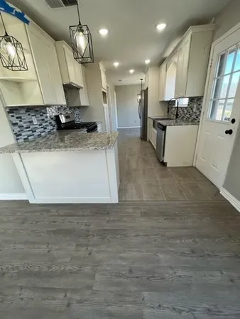 a view of kitchen with kitchen island stainless steel appliances a sink and wooden floor