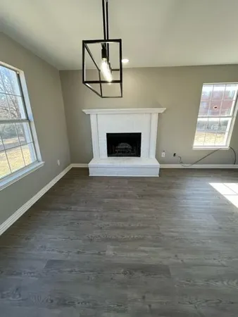 an empty room with windows and fireplace