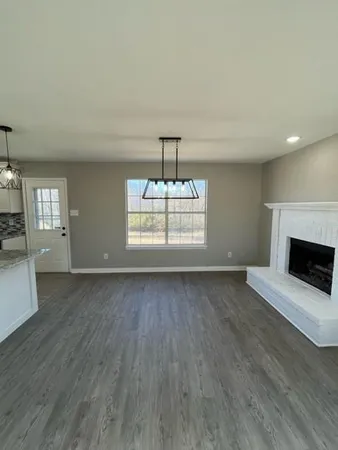 a view of a livingroom with wooden floor fireplace and window