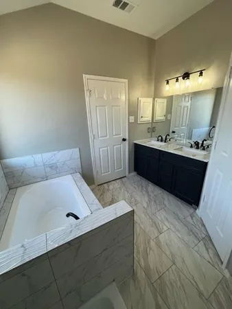 a large bathroom with a tub sink and mirror