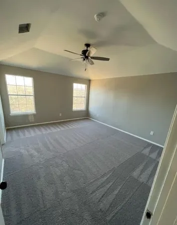 an empty room with windows and ceiling fan view