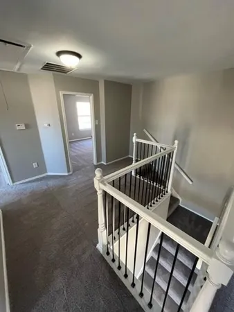 a view of staircase with railing and white walls