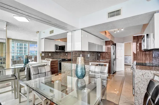 a kitchen with stainless steel appliances granite countertop a stove top oven a sink dishwasher and white cabinets with wooden floor