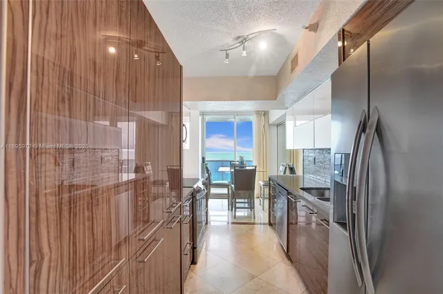 a kitchen with stainless steel appliances a refrigerator and a view of living room