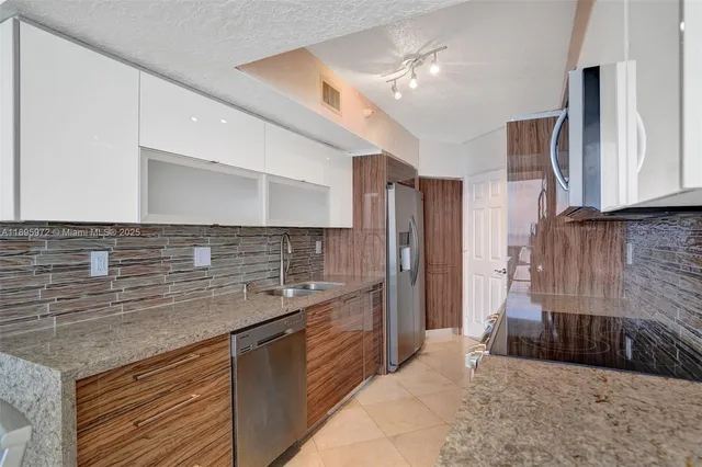 a kitchen with stainless steel appliances granite countertop a sink and a refrigerator