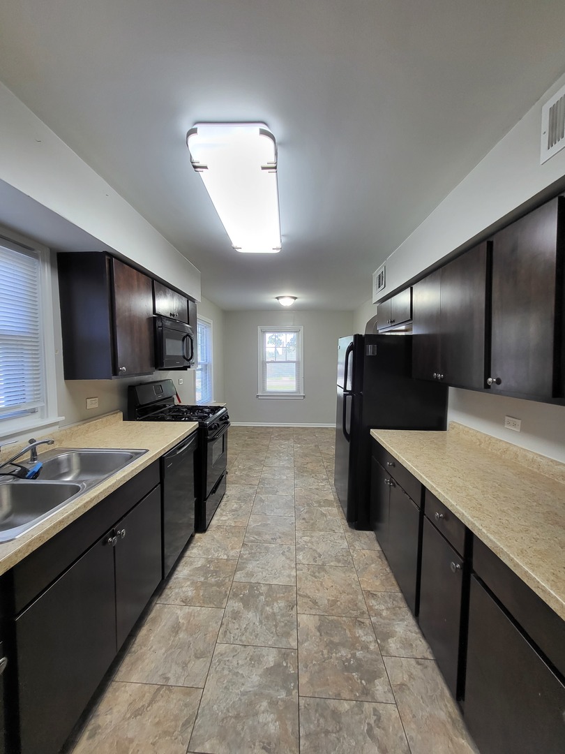 401 North Wolf Road Northlake, IL 60164 - Photo 2 of 15 a large kitchen with a large counter top sink and refrigerator