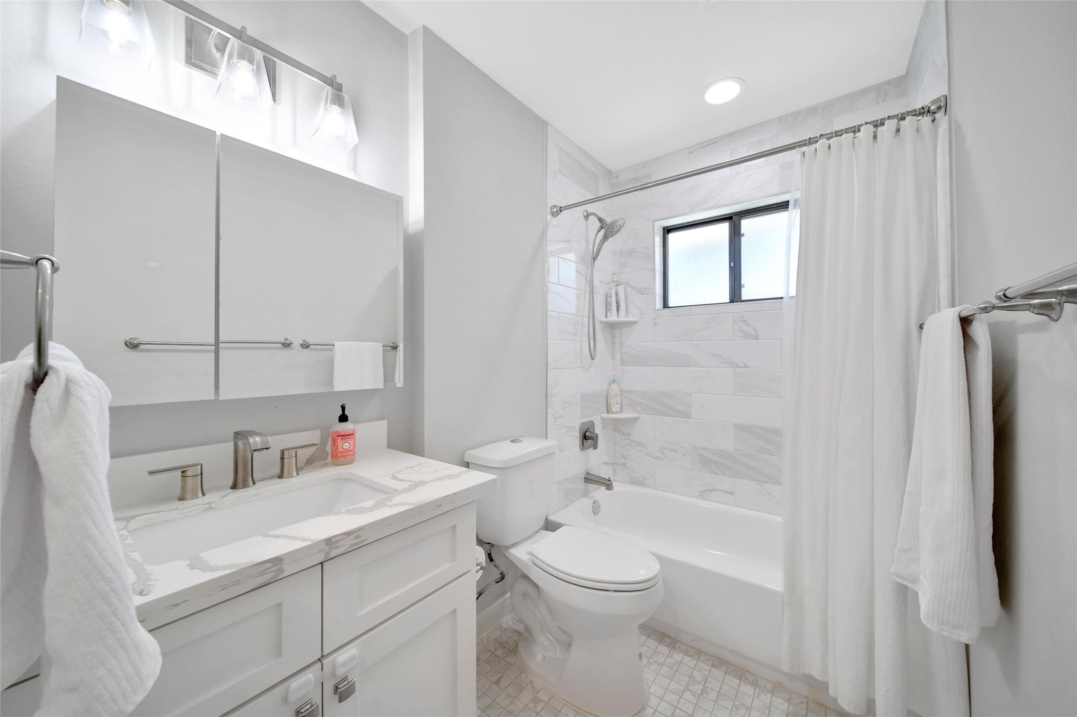 4402 Fallbrook Drive Houston, TX 77018 - Photo 24 of 29 Bright secondary bathroom with quartz countertops, sleek tilework, and a refreshed tub/shower area.
