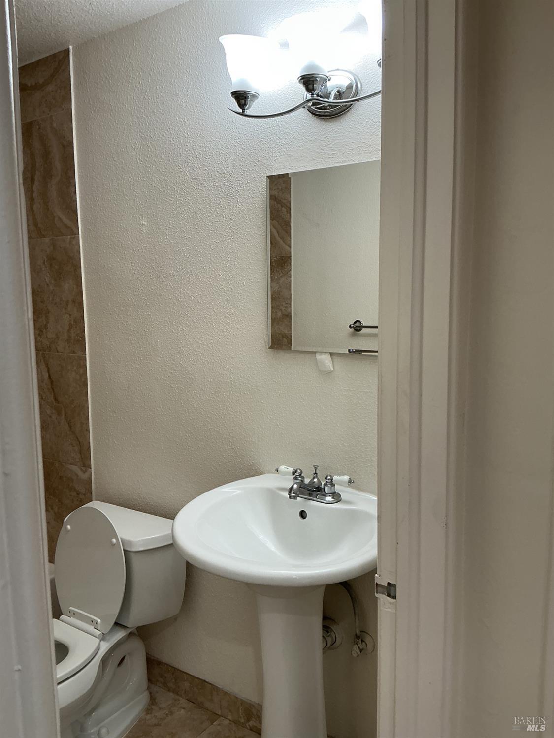 212 South E Street, Unit B Santa Rosa, CA 95404 - Photo 10 of 31 a bathroom with a sink a toilet and mirror