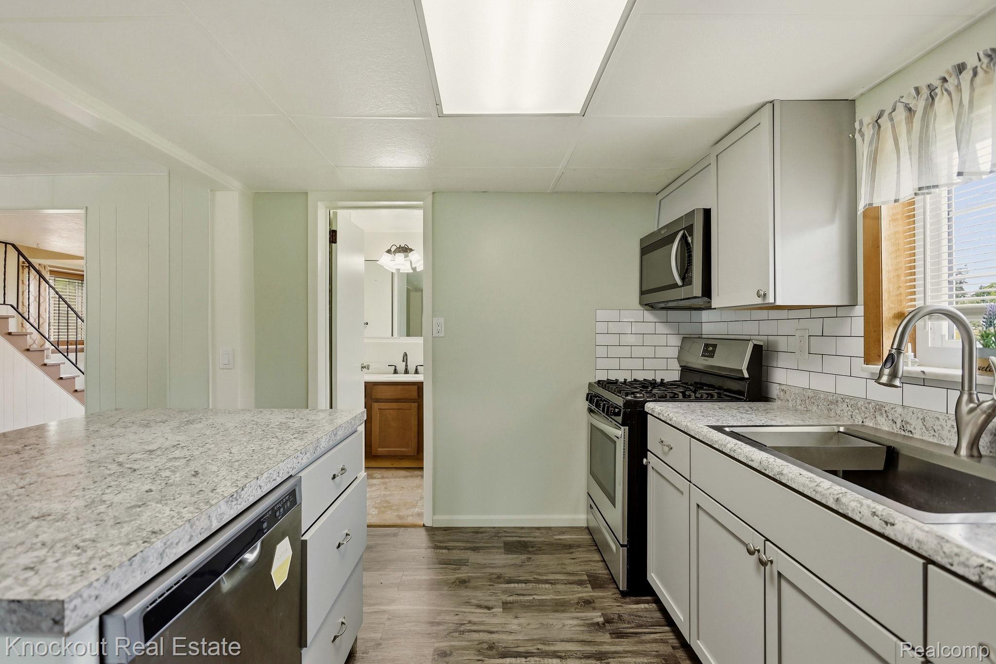 8771 Van Cleve Road Vassar, MI 48768 - Photo 17 of 44 Kitchen featuring light-toned cabinetry, stainless steel appliances, granite-style countertops, and a subway tile backsplash
