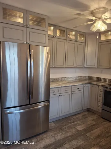 a kitchen with stainless steel appliances granite countertop a refrigerator a sink and white cabinets