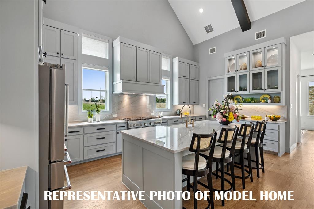 1120 Whirlabout Road Prosper, TX 75078 - Photo 5 of 12 a kitchen with stainless steel appliances granite countertop a stove top oven a sink a dining table and chairs with wooden floor