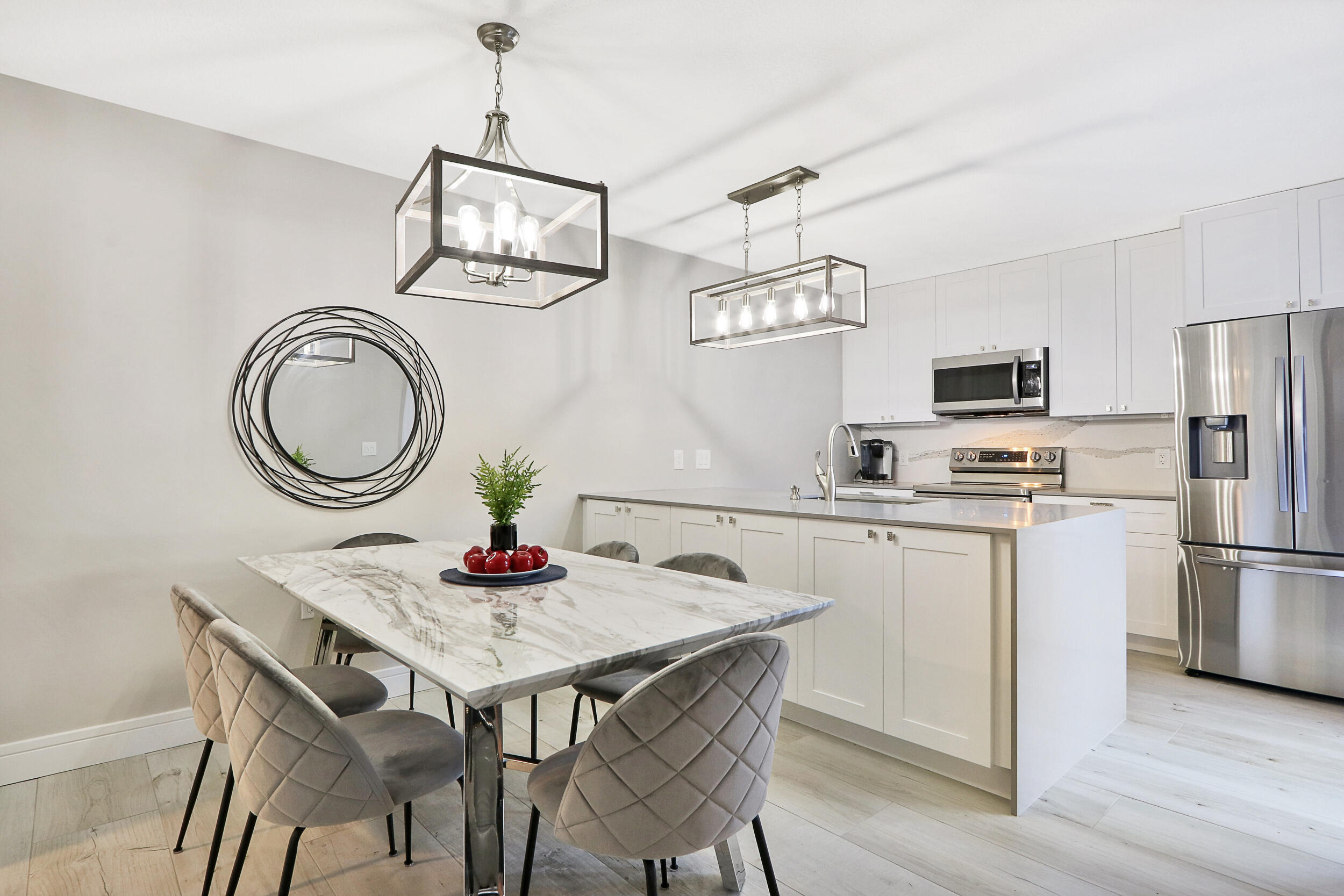 a kitchen with stainless steel appliances granite countertop a dining table chairs and white cabinets