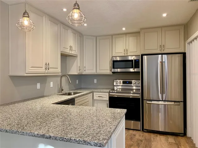a kitchen with stainless steel appliances granite countertop a sink stove and refrigerator