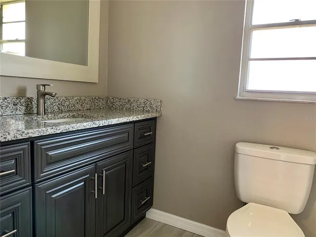a bathroom with a granite countertop toilet sink and mirror